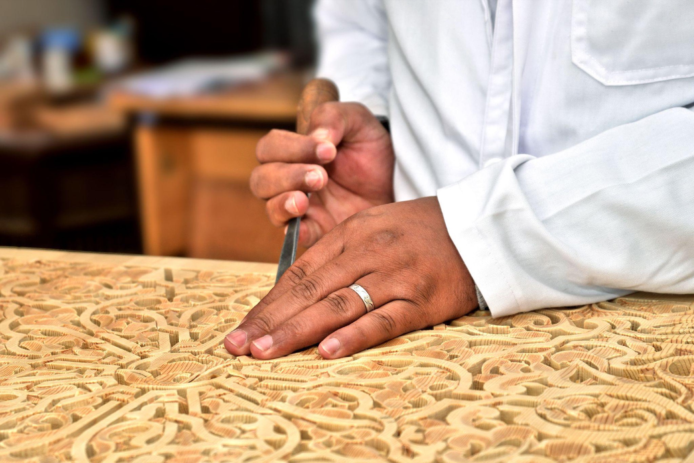 Hands carving an ornamental wooden panel